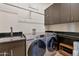 Well organized laundry room with granite countertops, modern washer and dryer, utility sink and storage cabinets at 10664 E Monument Dr, Scottsdale, AZ 85262