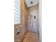 Walk-in shower with travertine tile, multiple shower heads, and a glass block window at 10664 E Monument Dr, Scottsdale, AZ 85262