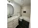 An updated bathroom features a marble-topped vanity, arched mirror, tub-shower combo, and sleek black marble floor at 11474 N 79Th Dr, Peoria, AZ 85345