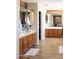 Bright bathroom featuring double sinks, tile floors, and a doorway to a walk-in closet for ample storage at 15148 W Sells Dr, Goodyear, AZ 85395