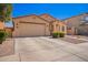 A tan single-story home featuring desert landscaping, a two-car garage and a comfortable aesthetic at 17693 W Lincoln St, Goodyear, AZ 85338
