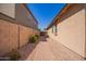 Narrow side yard featuring a brick pathway between the house and a block wall, with desert landscaping at 17693 W Lincoln St, Goodyear, AZ 85338