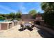 Cozy backyard stone patio with outdoor kitchen, fireplace, seating, and lush landscaping at 17975 W Willow Dr, Goodyear, AZ 85338