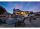 Exterior of home at dusk featuring a stone patio, outdoor kitchen with grill, and beautiful backyard at 17975 W Willow Dr, Goodyear, AZ 85338
