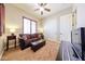 Bright living room featuring a brown couch, ottoman and shutters at 17975 W Willow Dr, Goodyear, AZ 85338