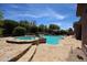 Beautiful pool with a rock waterfall feature and integrated hot tub, surrounded by desert landscaping at 17975 W Willow Dr, Goodyear, AZ 85338