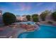 Relaxing backyard featuring a pool with waterfall feature, jacuzzi, comfortable seating, and colorful foliage at 17975 W Willow Dr, Goodyear, AZ 85338
