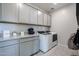 Well-organized laundry room with gray cabinetry, granite countertop, and modern washer and dryer at 18134 W Creedance Blvd, Surprise, AZ 85387