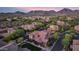 Aerial view of a residential community with tile roofs, mature trees, and a backdrop of scenic mountains at sunset at 18562 N 94Th St, Scottsdale, AZ 85255