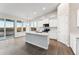 Bright kitchen featuring stainless steel appliances, grey wood flooring, a center island with sink, and a large glass door at 18931 W Crescent Way, Buckeye, AZ 85326