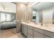 Bathroom with double sink vanity, a large mirror and neutral decor, connecting to a bedroom at 20251 W Madison St, Buckeye, AZ 85326