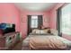 Bedroom featuring pink walls, a window with gray drapes, a TV and a wooden dresser at 20251 W Madison St, Buckeye, AZ 85326