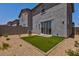 View of the backyard showcasing artificial turf, desert landscaping, and a sliding glass door to the home at 21047 N 58Th Way, Phoenix, AZ 85054