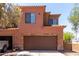 Exterior of two-story home featuring a brown garage door, stone accents, and clay tile roof at 21655 N 36Th Ave # 131, Glendale, AZ 85308
