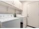 Bright laundry room with white appliances, cabinetry, tile floor, and convenient access door at 2615 N 123Rd Dr, Avondale, AZ 85392