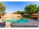 Refreshing swimming pool surrounded by desert landscaping, mature trees, and a privacy wall at 2615 N 123Rd Dr, Avondale, AZ 85392