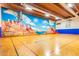 Spacious indoor basketball court with hardwood floor, hoops, and vibrant desert-themed mural at 3031 N Civic Center Plz # 355, Scottsdale, AZ 85251