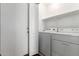 Compact laundry area featuring a washer, dryer, shelving, and a door at 30601 N Royal Oak Way, San Tan Valley, AZ 85143