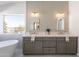 Spa-like bathroom featuring dual vanities, modern lighting, soaking tub, and a window at 3837 E Windsong Dr, Phoenix, AZ 85048