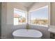 A freestanding soaking tub has a relaxing view out of the picture window at 3837 E Windsong Dr, Phoenix, AZ 85048