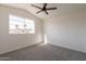Carpeted bedroom featuring a ceiling fan and a window providing neighborhood views at 3837 E Windsong Dr, Phoenix, AZ 85048