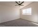 Bright carpeted bedroom with a ceiling fan and a window showcasing views of the neighborhood at 3837 E Windsong Dr, Phoenix, AZ 85048