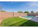 A beautiful pool enclosed by a brick wall, a grassy lawn, and decorative rock landscaping at 3837 E Windsong Dr, Phoenix, AZ 85048
