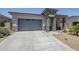 Front exterior view of a home with a stone-accented facade, a wide driveway, and desert landscaping at 40848 W Hillman Dr, Maricopa, AZ 85138