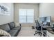 Cozy home office featuring a comfortable couch, modern desk, and window providing natural light at 40848 W Hillman Dr, Maricopa, AZ 85138