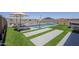 Backyard pool and spa area featuring lounge chairs, artificial grass, and decorative wall art at 40848 W Hillman Dr, Maricopa, AZ 85138