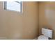 A half-bathroom featuring a toilet and a window allowing natural light at 4432 W Pleasant Ln, Laveen, AZ 85339