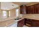A kitchen with dark wood cabinets, stone countertops, stainless steel sink, and adjacent breakfast bar at 4432 W Pleasant Ln, Laveen, AZ 85339