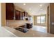 Spacious kitchen features dark wood cabinets, stone countertops, tiled backsplash, and a stainless steel sink at 4432 W Pleasant Ln, Laveen, AZ 85339