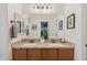 Bathroom featuring double sink vanity with granite counters, framed mirror, and walk-in closet at 4772 E Portola Valley Dr # 102, Gilbert, AZ 85297