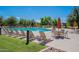 Community pool surrounded by lounge chairs, tables, umbrellas, and green grass at 4772 E Portola Valley Dr # 102, Gilbert, AZ 85297