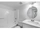 Clean bathroom features white tiled shower-tub, a round mirror, and a vanity with solid surface countertop at 5504 N 69Th Ave, Glendale, AZ 85303