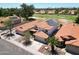 An aerial view of a home with solar panels, desert landscaping, and a community near a golf course at 7535 W Kimberly Way, Glendale, AZ 85308