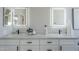 Double vanity featuring white cabinets, sleek black hardware, modern fixtures, and illuminated mirrors at 7535 W Kimberly Way, Glendale, AZ 85308