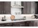 Modern kitchen features white counters, marble backsplash, stainless hood, and cooktop with dark wood cabinets at 8055 E Jaeger St, Mesa, AZ 85207