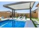 Relaxing in-pool seating area with modern pergola, waterfall feature, and lush landscaping offers a luxurious outdoor retreat at 8055 E Jaeger St, Mesa, AZ 85207