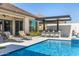 Relaxing pool area featuring sun loungers, covered outdoor kitchen with bar, and a beautiful in-ground pool with cool, blue water at 8055 E Jaeger St, Mesa, AZ 85207