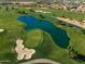 Aerial view of a scenic golf course featuring lush green fairways, a tranquil lake, and sand bunkers at 841 E Farmers Ln, Queen Creek, AZ 85140
