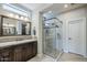 Bathroom with neutral walls, a sink vanity with dark cabinets, and glass-enclosed shower featuring pebble flooring at 841 E Farmers Ln, Queen Creek, AZ 85140