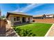 Home boasts a large manicured synthetic lawn, a covered patio, and is surrounded by brick fencing at 10059 E Tamery Ave, Mesa, AZ 85212