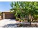 Well-maintained home exterior with a two-car garage, desert landscaping, and a paved driveway under a tree at 10059 E Tamery Ave, Mesa, AZ 85212