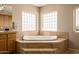 A bathroom showcasing a soaking tub surrounded by stone tile and natural light from the glass block windows at 10386 N 96Th Pl, Scottsdale, AZ 85258