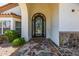View of the front door area including the wrought iron door, stone archway, and stone tile walkway at 10386 N 96Th Pl, Scottsdale, AZ 85258