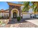 Close-up view of an arched stone entryway and a decorative wrought iron door for beautiful curb appeal at 10386 N 96Th Pl, Scottsdale, AZ 85258