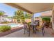Covered patio with a table and chairs, overlooking the pool and landscaped backyard at 1142 E Mayfield Dr, San Tan Valley, AZ 85143