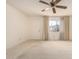 Neutral carpeted living room featuring a ceiling fan, bright window views, and ample natural light at 11627 S Iroquois Dr, Phoenix, AZ 85044
